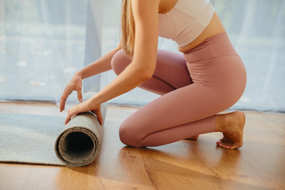 devojka prostire prostirku za jogu